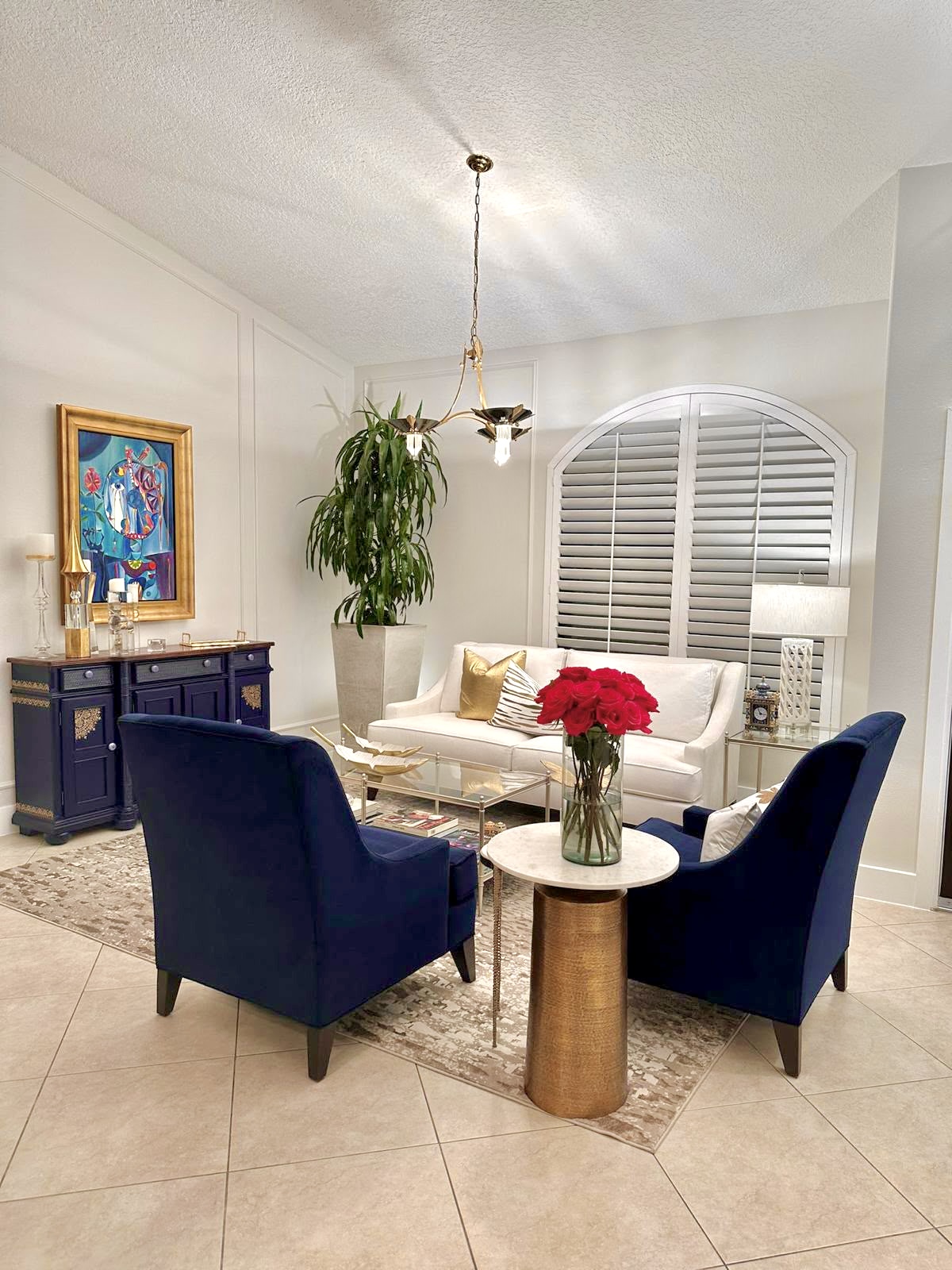 An elegant living room with navy armchairs and fresh red roses cleaned by Sparkle Cleaning Services