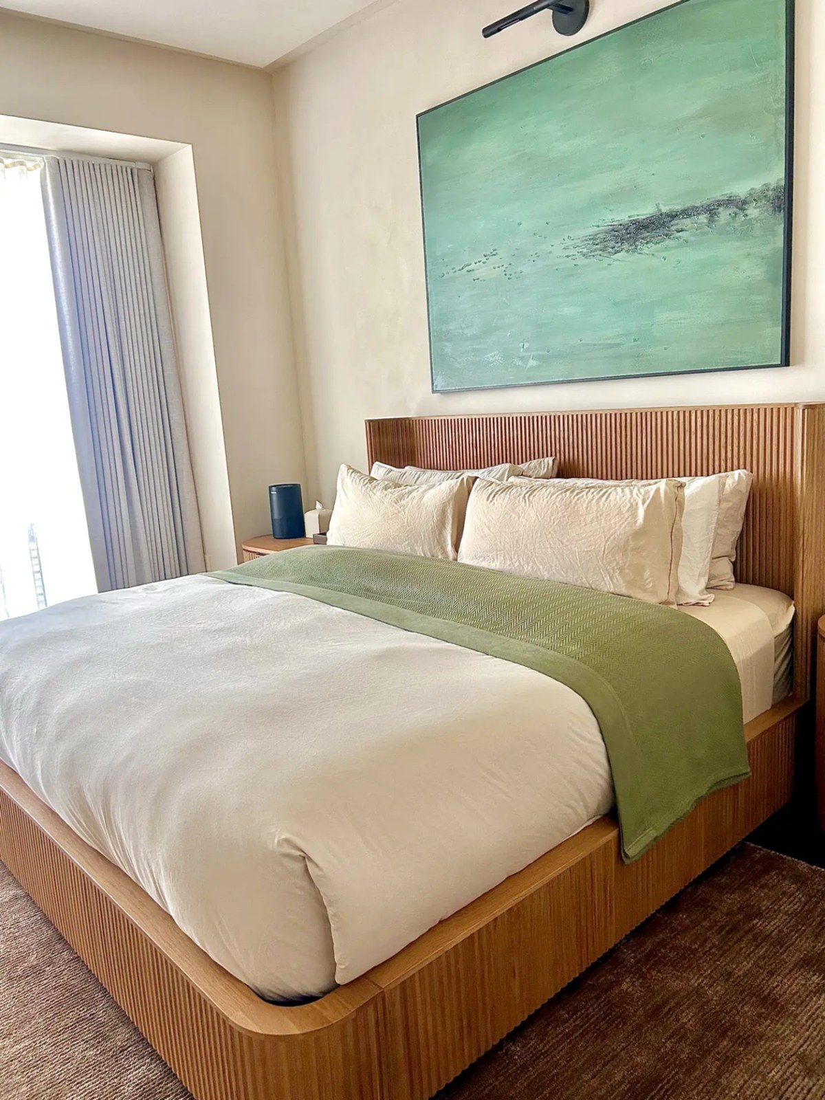 A serene master bedroom with a fluted wood bed frame and neatly styled bedding after a Sparkle cleaning