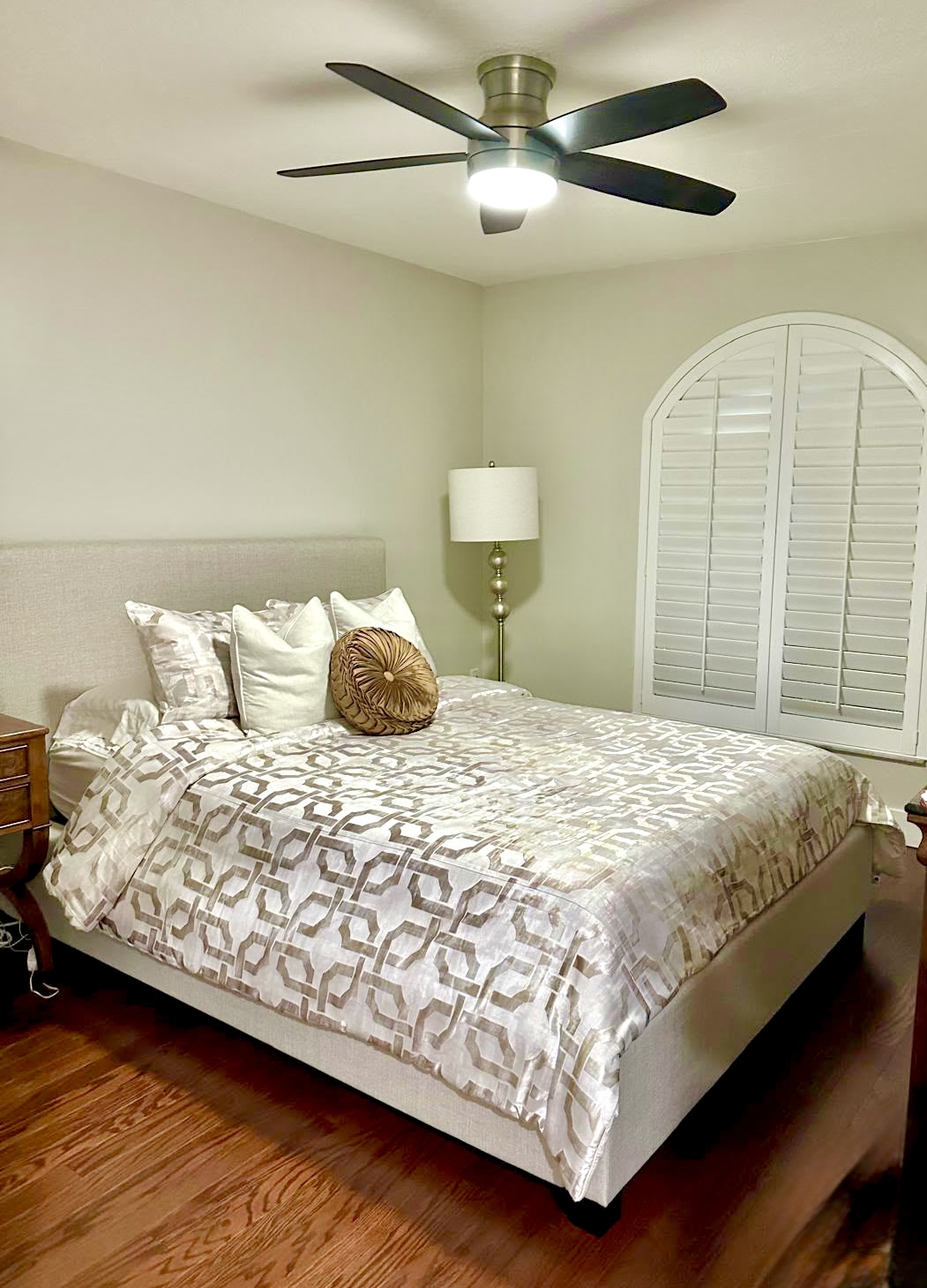 A freshly made guest bedroom with crisp linens and polished hardwood floors
